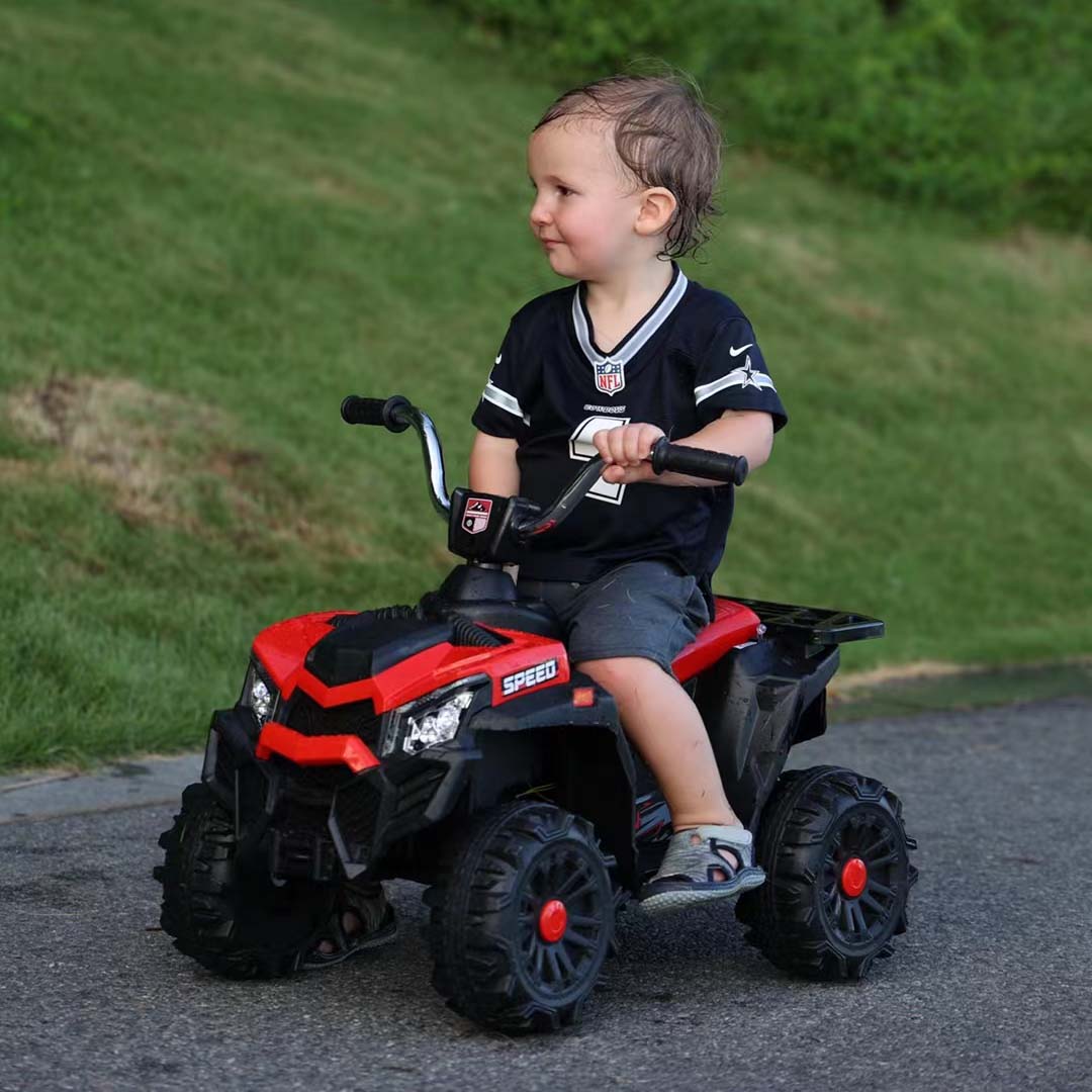 Enfant souriant sur quad électrique rouge